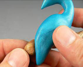 Blue clay being pressed onto clay branch